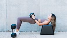 woman doing glute bridge with dumbbell