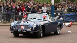 Prince William and Kate Middleton drive from Buckingham Palace to Clarence House in a decorated vintage Aston Martin sports car on April 29, 2011