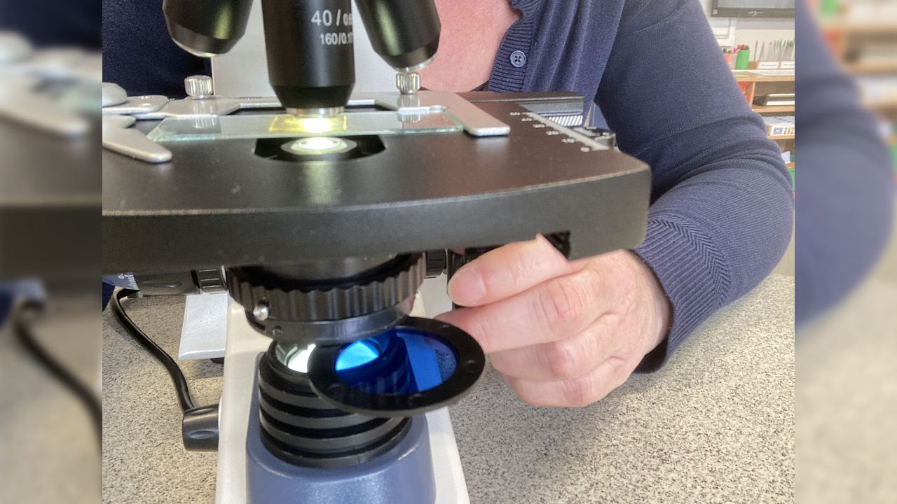 The microscope condenser swinging out with person manipulating the control