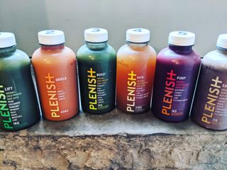 six bottles of plenish juices in a line