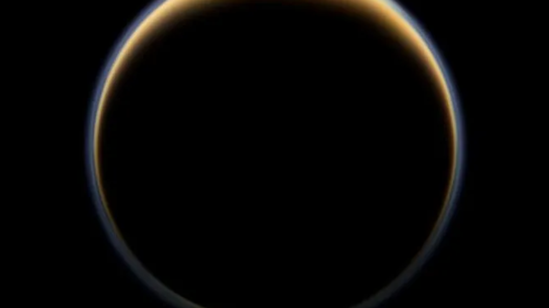 A dark sphere bounded by a brownish-yellow ring that is thicker at the north pole of the sphere