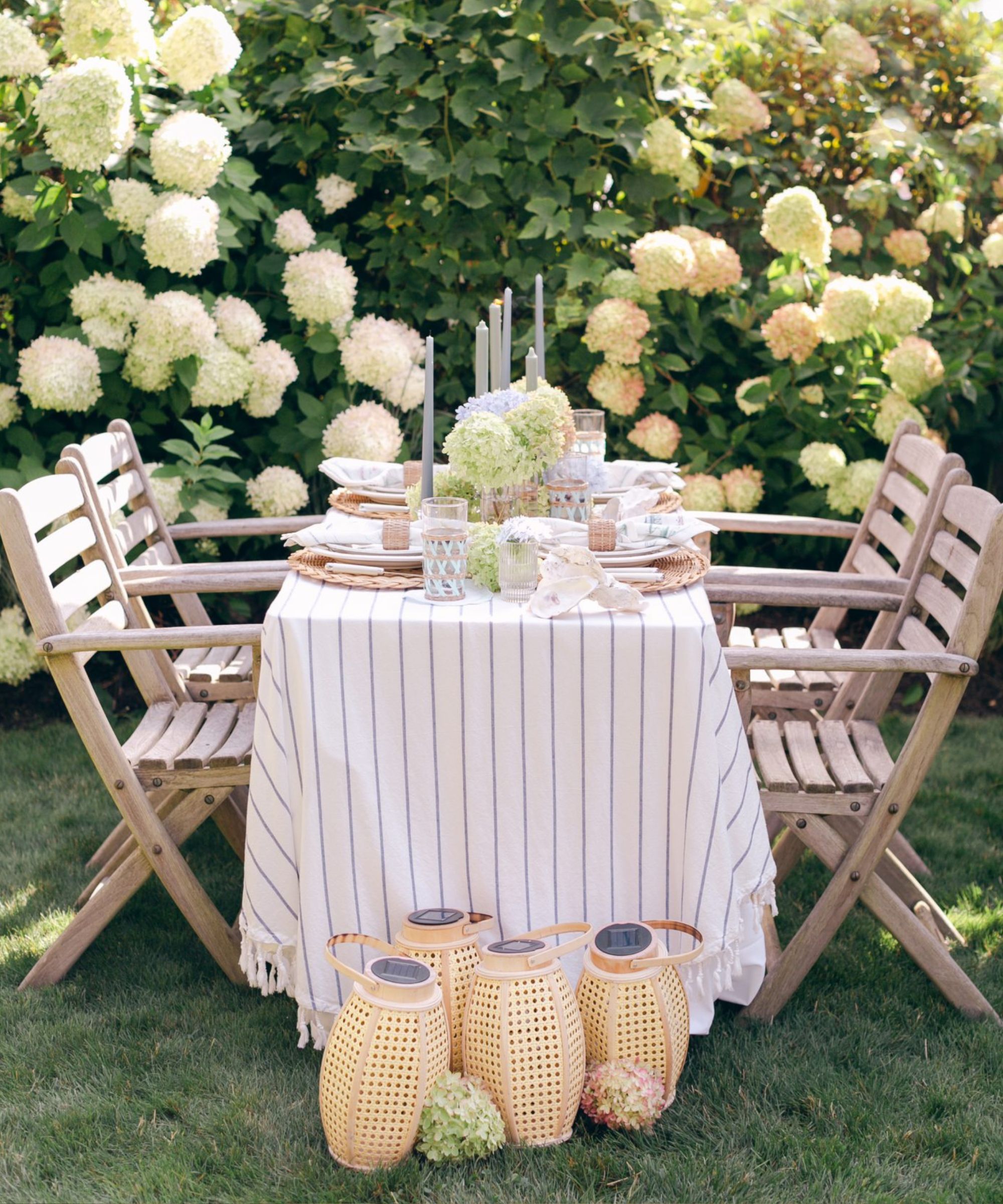 Summer outdoor dining table styled with hydrangeas picked from the garden and rattan lanterns