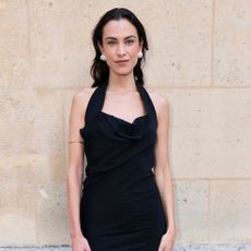 Alexa Chung wears a black halterneck dress with white heels and a black bag in Paris.