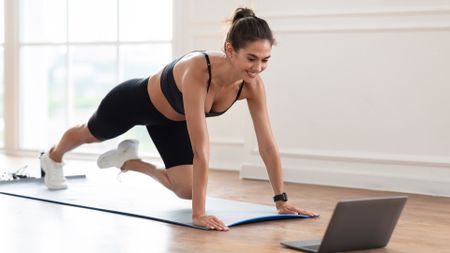 A woman following an online workout on her laptop