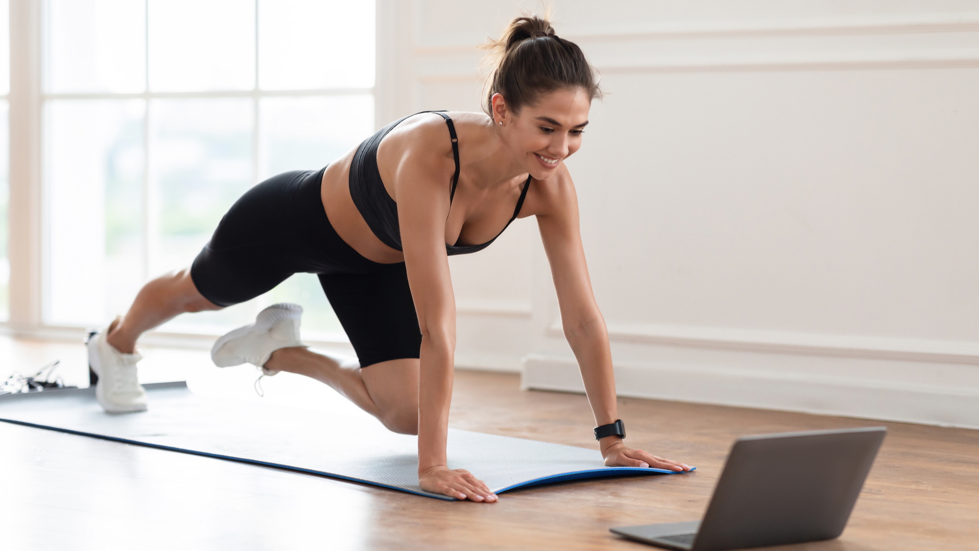 A woman following an online workout on her laptop