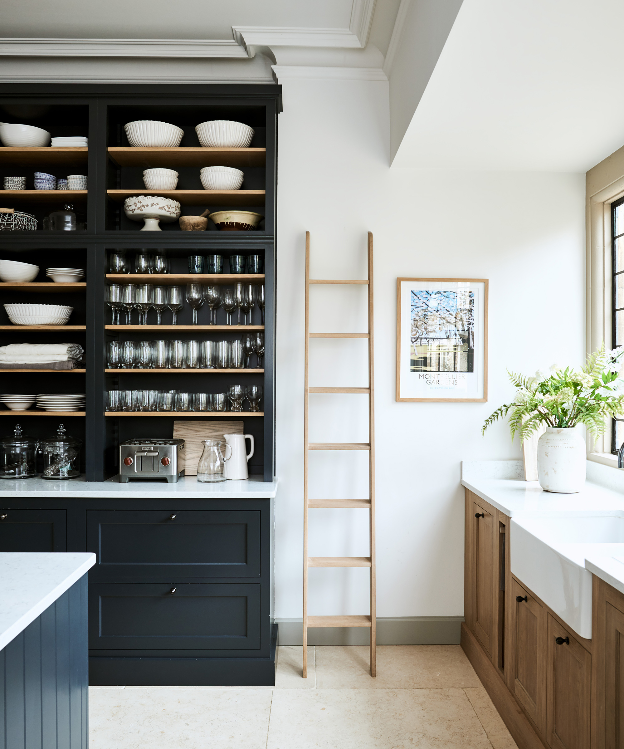 A white kitchen with black and unfinished wood cabinetry, ladder leaning on the wall