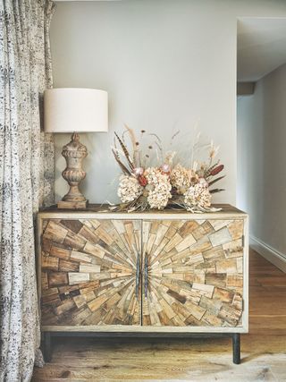 textured wood cabinet with dried flower display on top