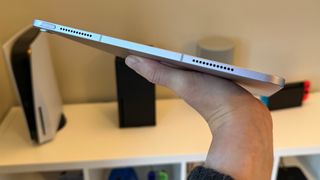 The 13-inch iPad Air being held flat on one hand, showing the bottom edge.