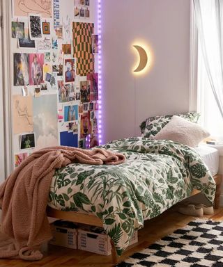 A small bedroom with bed, green and white botanical duvet set, monochrome checkered rug decor, purple LED strip lighting and gallery wall