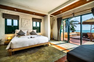 A room at the Aleenta Hua Hin - Pranburi hotel in Thailand with a large bed and outdoor space with views of the water