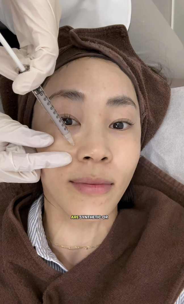 an asian woman receiving injections of Re02 while wearing a brown towel on her head