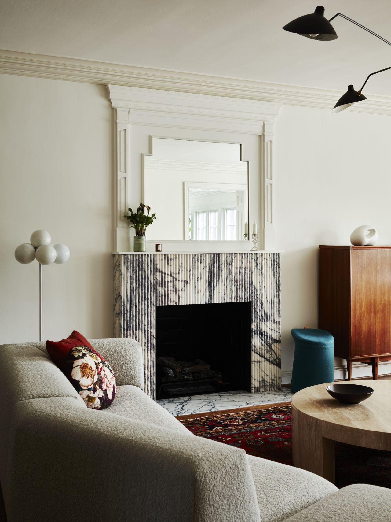A living room with white and cream sofas, marble fireplace, and red carpet
