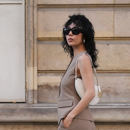 woman with cool tousled hair walking down the street wearing a beige waistcoat and sunglasses - Best hair creams 