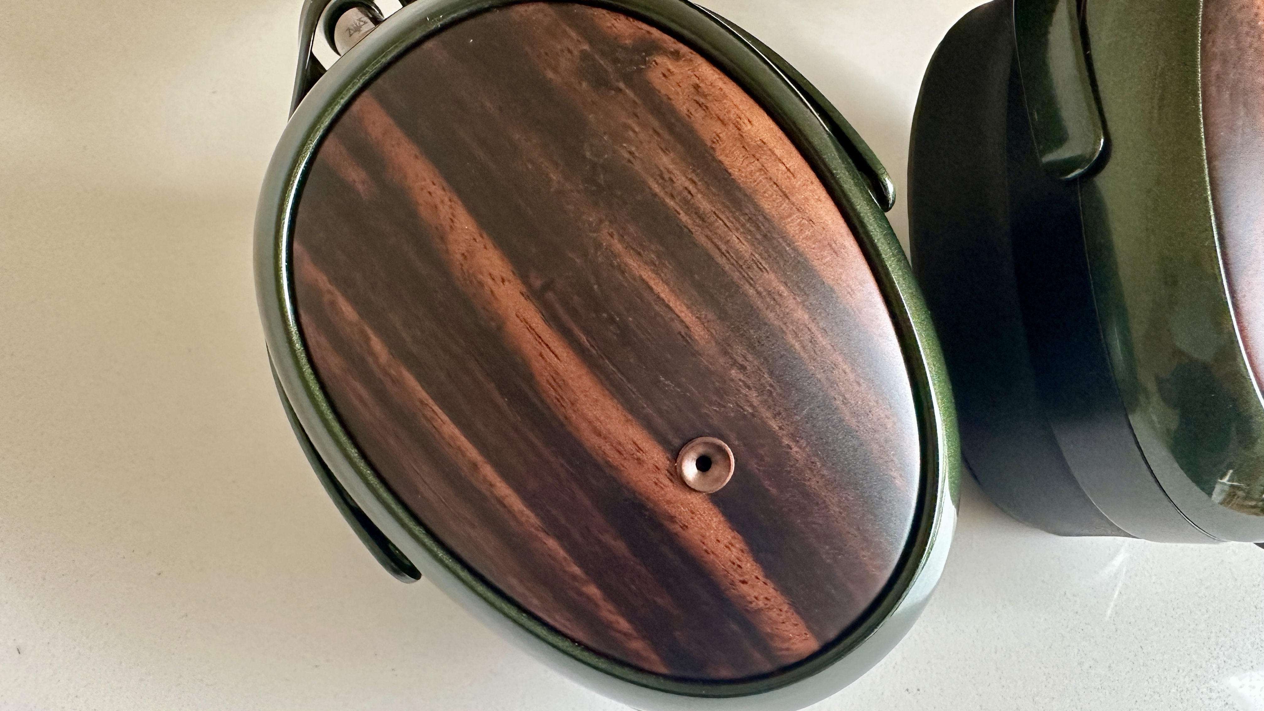 Meze Audio Strada headphones with wooden ear cups, in close-up and with their case and cables visible, on a white table