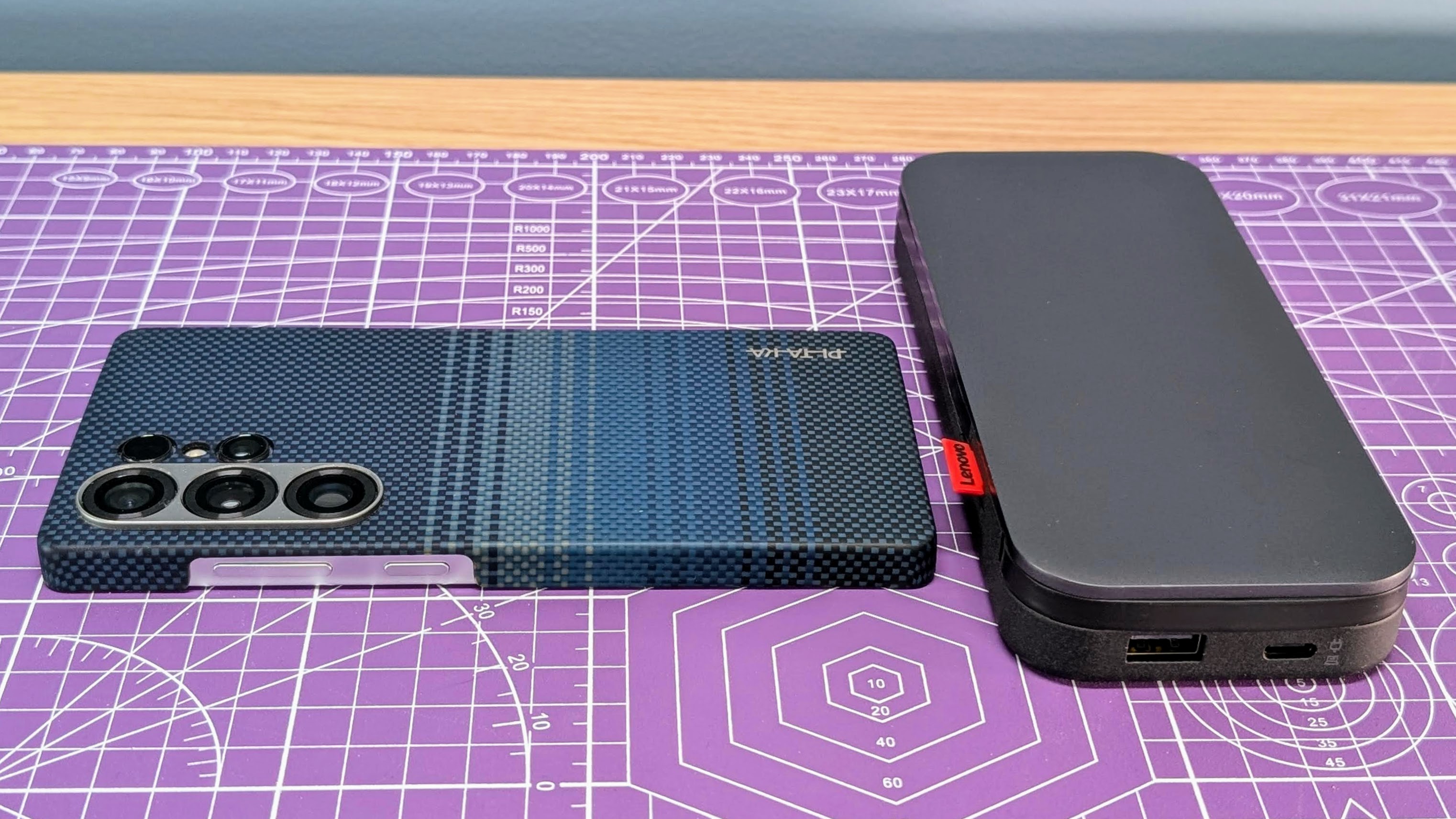 Lenovo Go USB-C laptop power bank with a Samsung Galaxy S25 Ultra smartphone sitting next to it as a size comparison