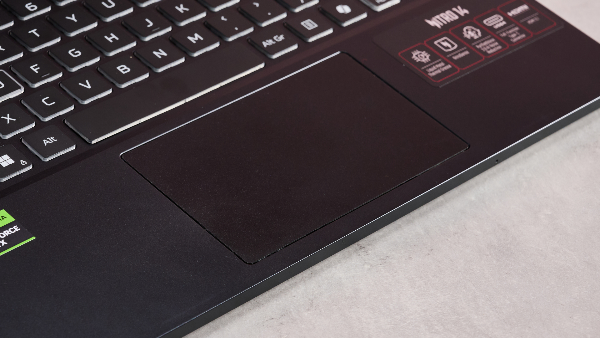 The Acer Nitro 14 compact gaming laptop photographed on a coral background.