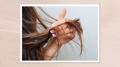 A close up of a woman holding the ends of her hair in her hand/ in a pink textured template