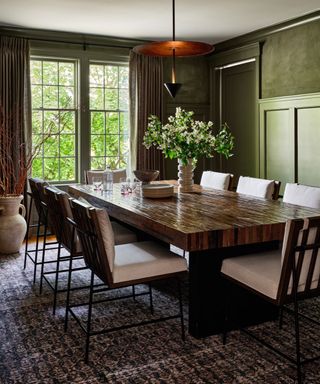 Green dining room with low hanging pendant, dark wood dining table and chairs