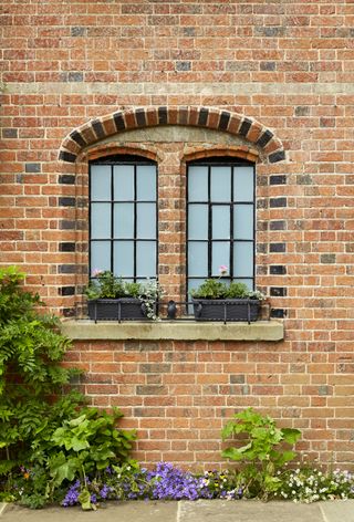 Leaded-windows-in-a-brick-wall-with-flowers