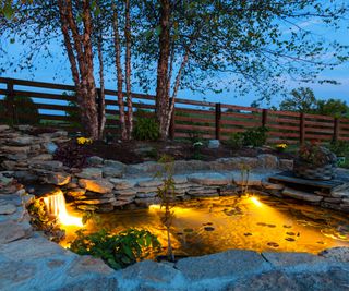 An outdoor pond built with stones and lit with a golden light