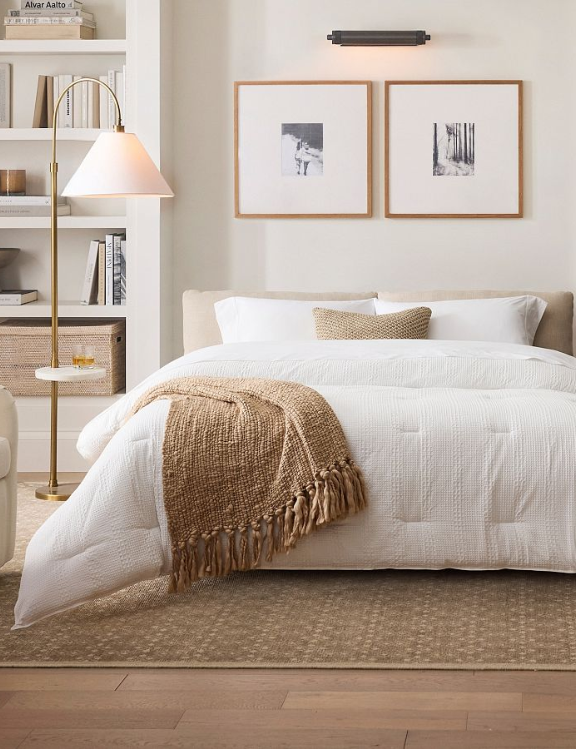 Pottery barn sleeper sofa made up for guests, styled alongside a floor lamp-tiny table combo and modern artwork