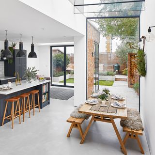 A side return extension with glass wall and ceiling in a modern open plan living area with wooden table and benches