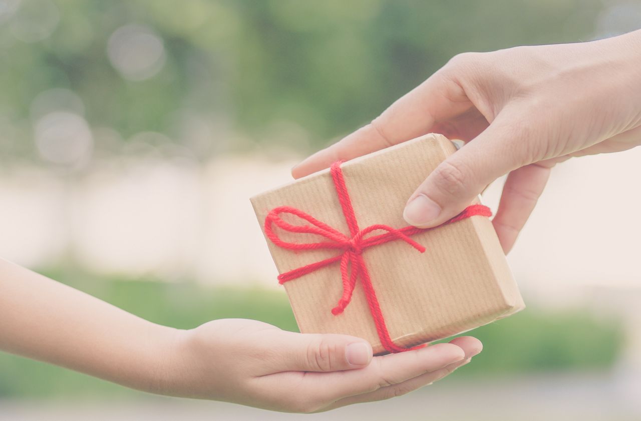 Holidays, present, christmas, childhood and happiness concept - close up of child and mother hands with gift box over green background. Vintage style.