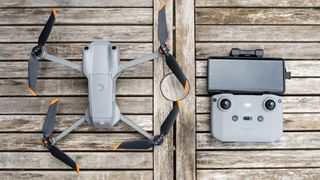 The DJI Air 2S drone sitting next to its controller on a wooden table