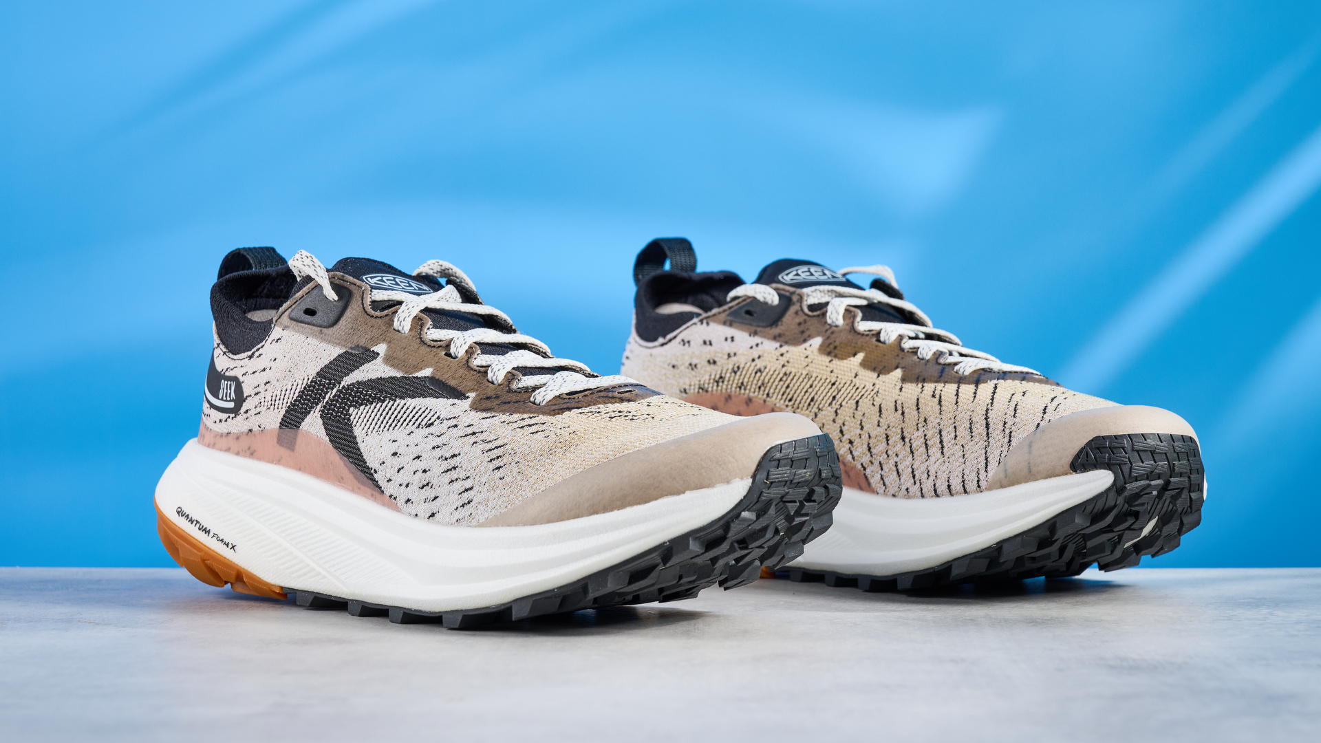 the keen seek trail shoes in brown, black, and beige photographed against the blue tom's guide background