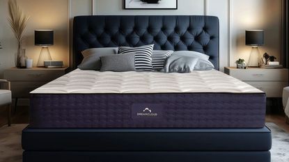 DreamCloud Luxury Hybrid Mattress on a blue bed frame against a white wall; a nightstand either side. 