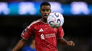 Alexander Isak, wearing the red of Liverpool, looks ahead at the ball during a match.