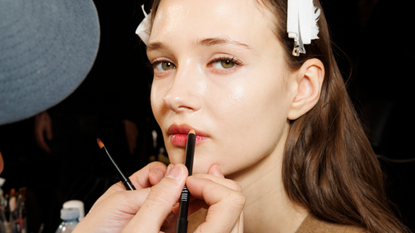 A makeup artist works on a model backstage ahead of the Luisa Spagnoli fashion show during the Milan Fashion Week Womenswear Fall/Winter 2024-2025 on February 25, 2024 in Milan, Italy. 