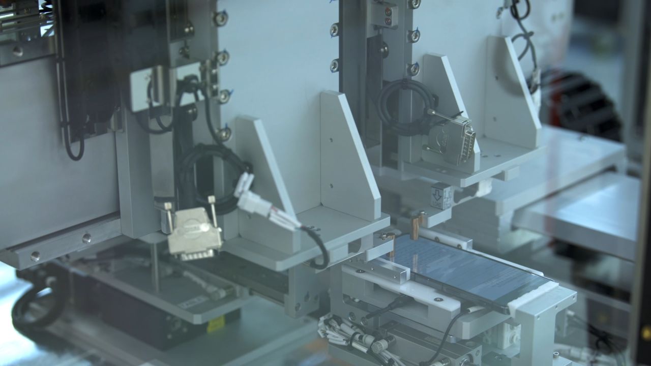 Robot arm typing on a Samsung phone in the automation testing lab