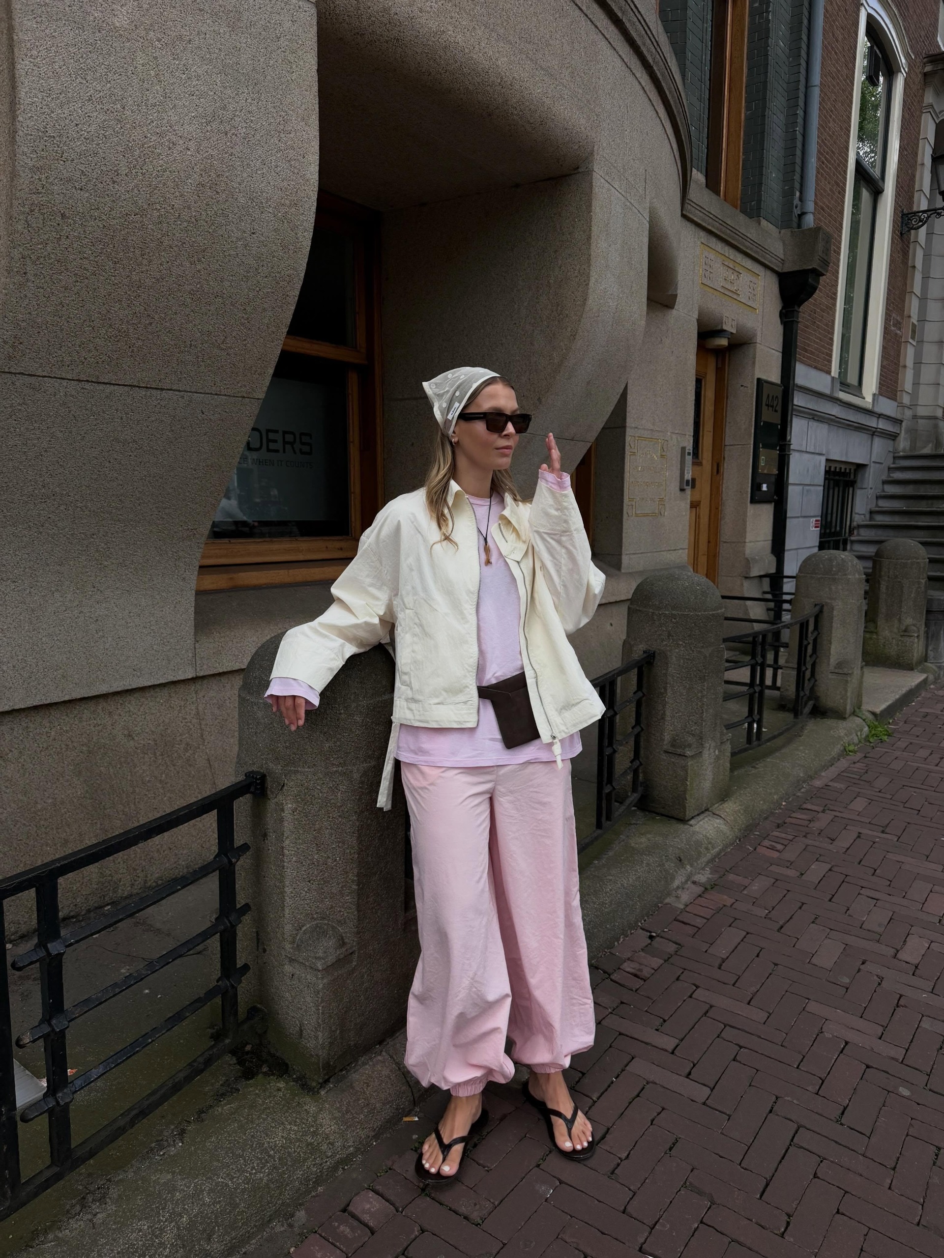 Colourful capsule wardrobe autumn 2026: Evie Mills. She wears a baby pink faux fur jacket. She styles it with a zebra-print clutch, zebra-print boots and a black top and Bermuda shorts.