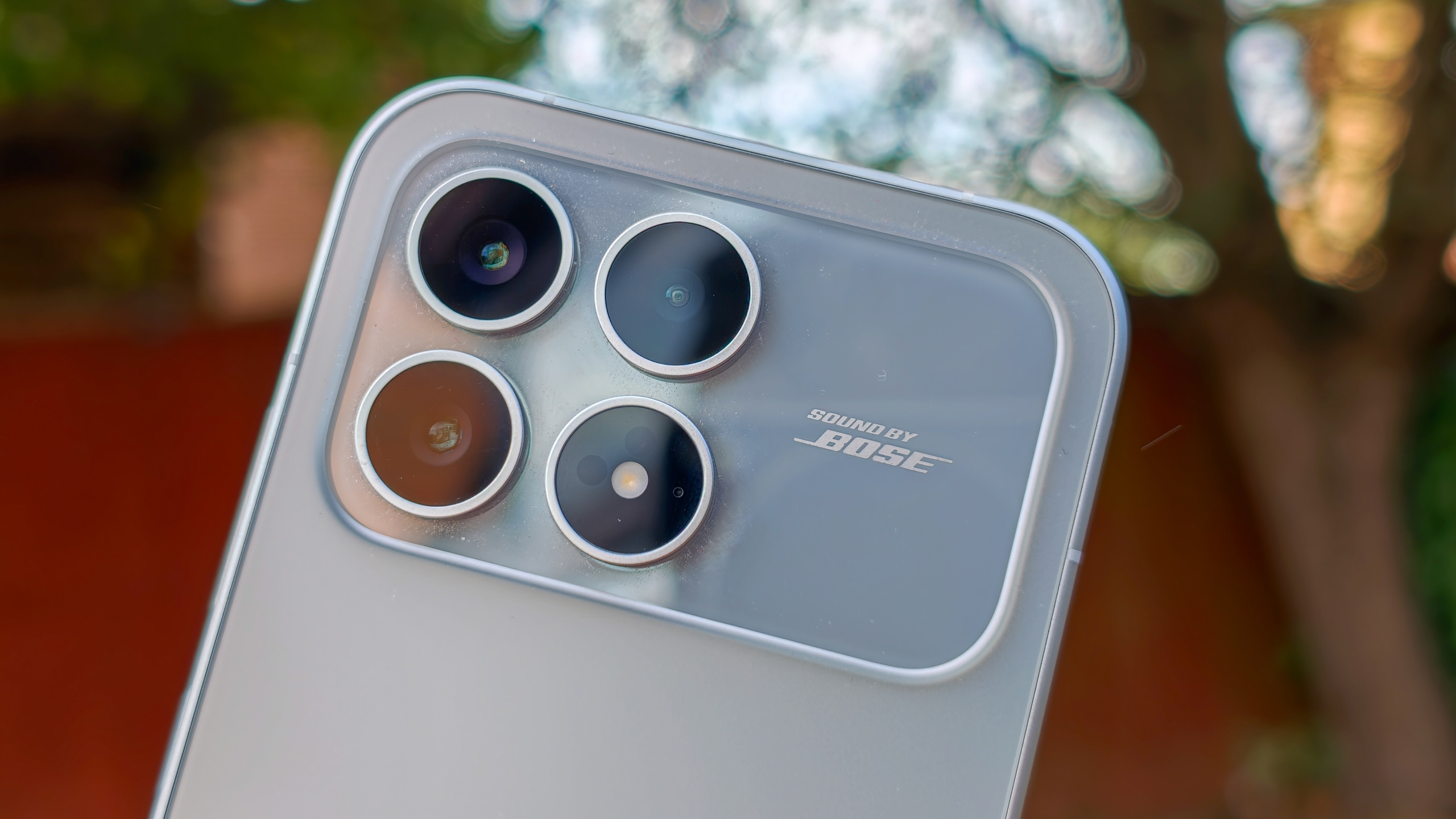 The Poco F8 Pro in Silver in the hand against a garden backdrop