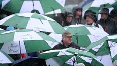 Patrons take cover from the rain around the 18th green during the third round of the 2023 Masters Tournament at Augusta National Golf Club on April 08, 2023