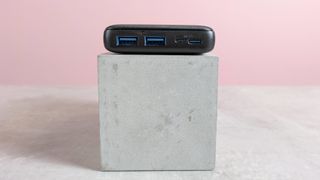 USB ports on Anker PowerCore Essential 20000 on plinth on desk with pink background