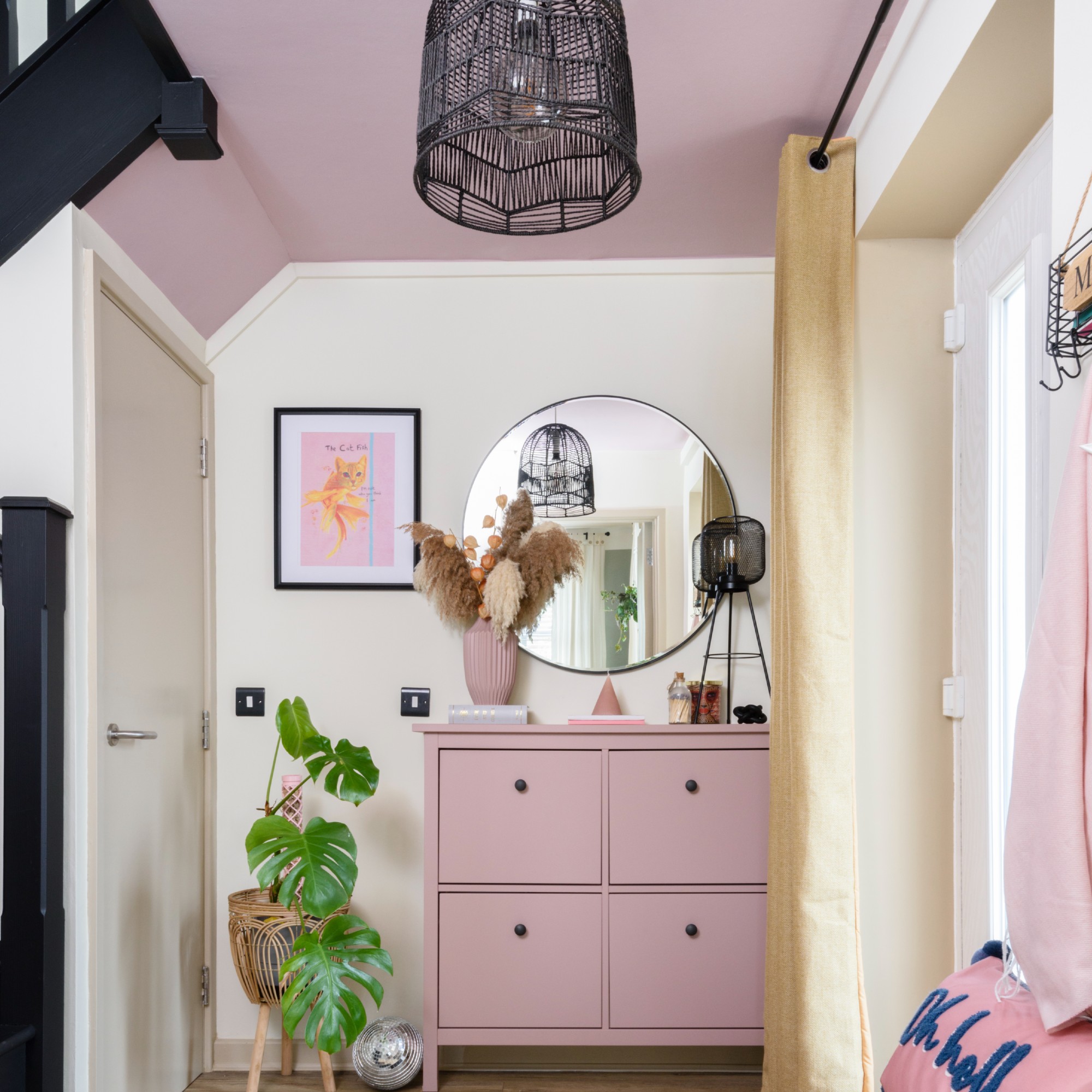 A hallway with a pink ceiling and matching pink shoe cabinet and off-white walls