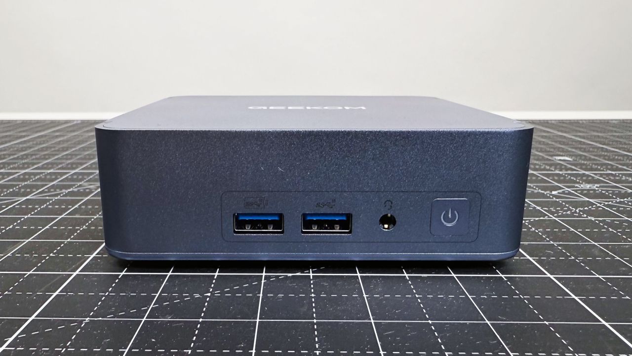 Close up of the front ports on the Geekom AX8 Pro AI Mini PC on a black mat against a white background.
