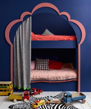 built in bunk beds with decorative arch opening framed in pink with navy blue walls to side and above