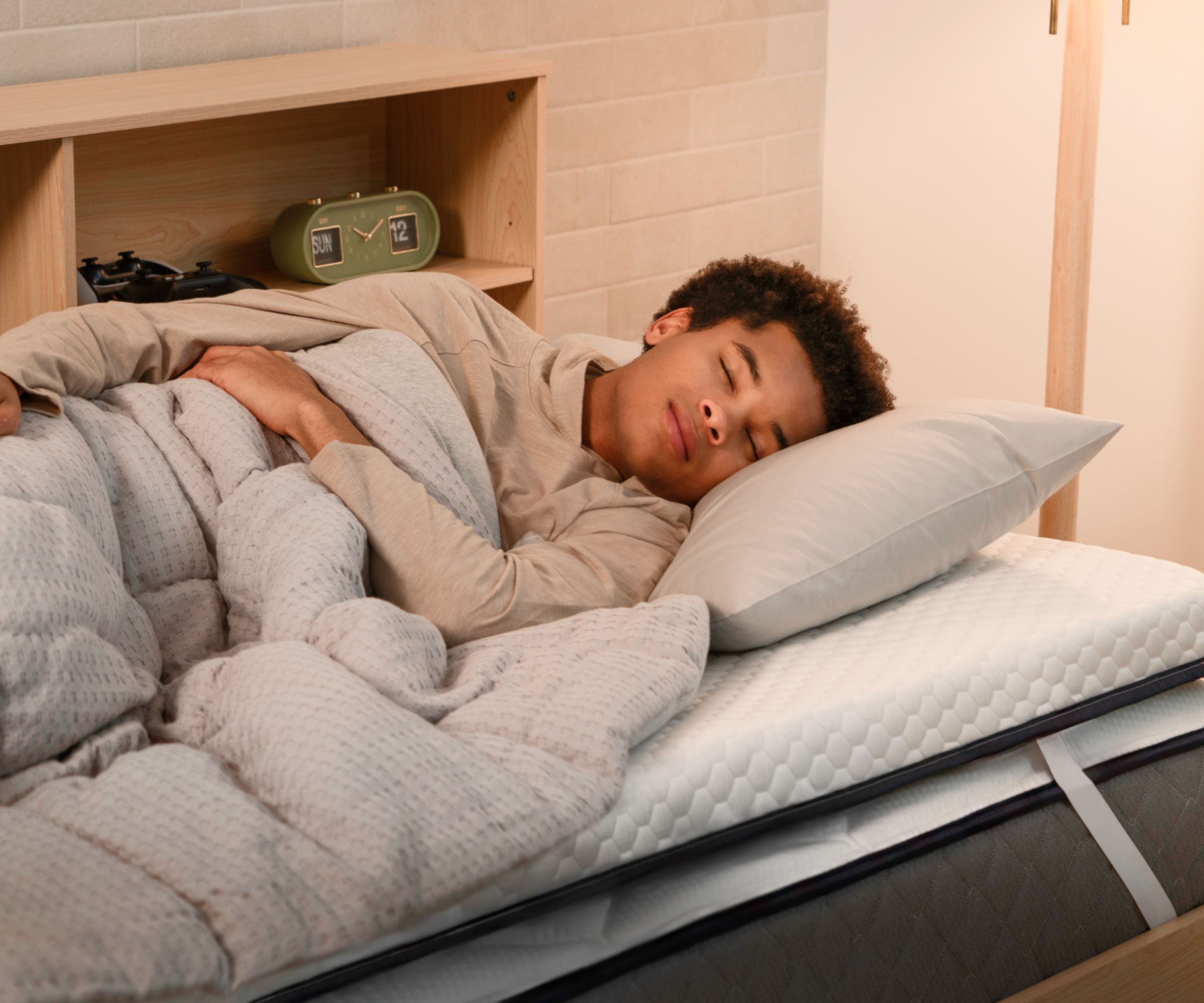 Teenager asleep on a bed showing mattress topper