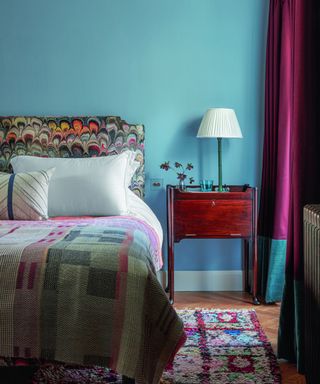 bedroom with blue walls and patterned throw and headboard