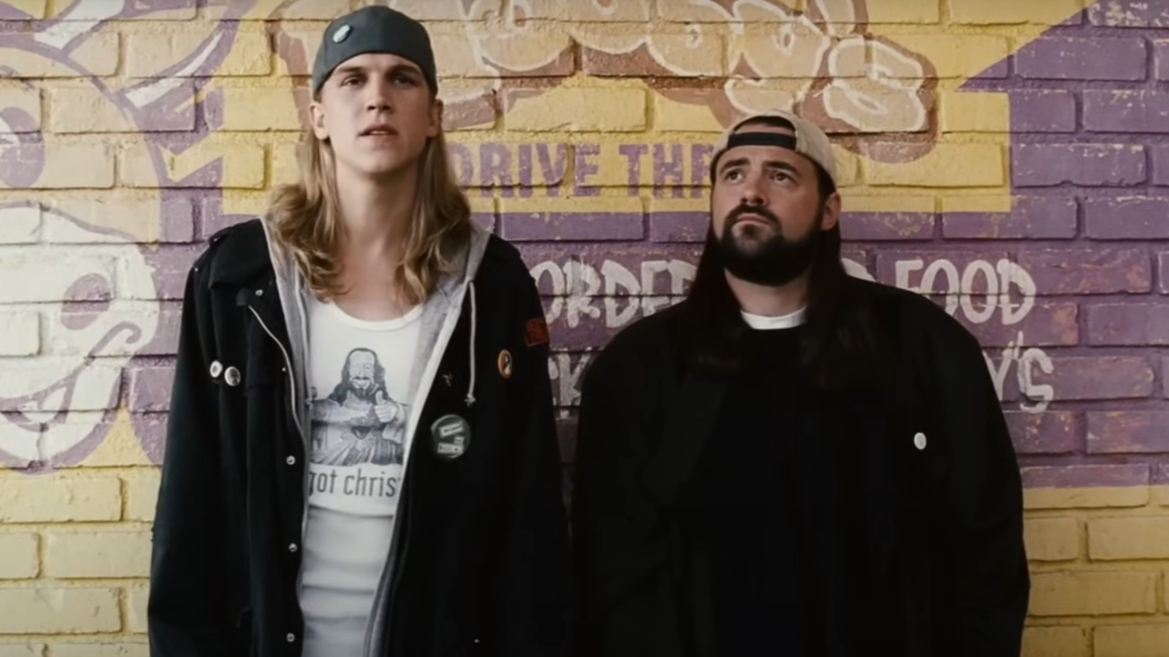Jay Mewes and Kevin Smith stand talking together with their backs against the Mooby's wall in Clerks II.