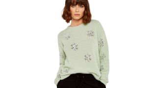 best christmas jumpers as illustrated with a pale green jumper covered in sequin snowflakes