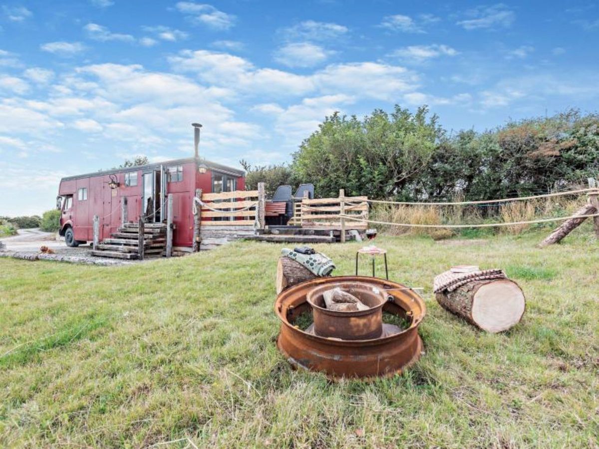 The outside of the caravan shows a firepit