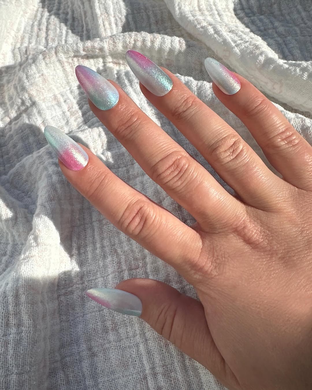 iridescent blue and purple sheen nails pictured over white fabric