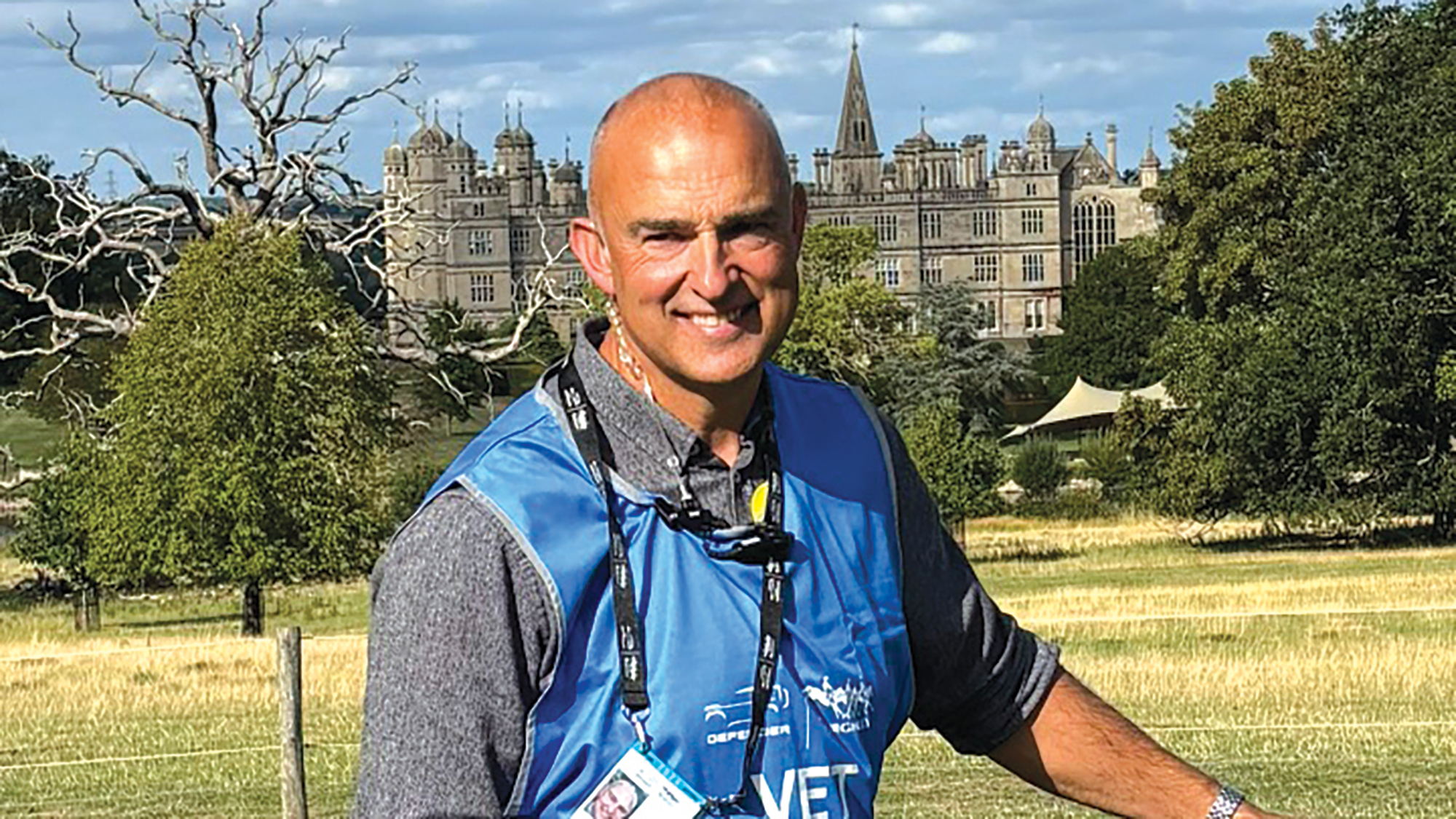 Vet Chris Johansson wearing a blue vest with "VET" written on it with Burghley House in the background