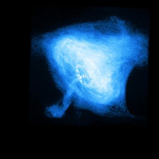 In the Crab Nebula, a rapidly rotating neutron star, or pulsar (white dot near the center), powers the dramatic activity seen by the Chandra X-ray Observatory. The inner X-ray ring is thought to be a shock wave that marks the boundary between the surrounding nebula and the flow of matter and antimatter particles from the pulsar.