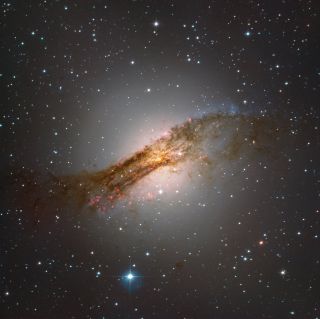 The oddly shaped galaxy Centaurus A glistens in deep space in this view from the European Space Agency's new SPECULOOS observatory in Chile. This was one of the "first light" images from SPECULOOS (which stands for "Search for habitable Planets EClipsing ULtra-cOOl Stars"). Centaurus A, also known as NGC 5128, is one of the brightest objects in the night sky of the Southern Hemisphere. It's located 11 million light-years from Earth in the constellation of Centaurus. Astronomers believe that Centaurus A was once an elliptical galaxy that collided with a small spiral galaxy, and that this collision is responsible for the galaxy's irregular shape.