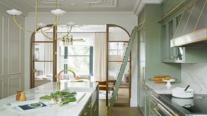 kitchen with arched wooden doorway, marble worksurfaces, an island and green cabinets